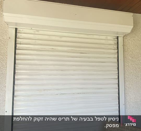 תריס גלילה לבן מותקן על קיר חיצוני
